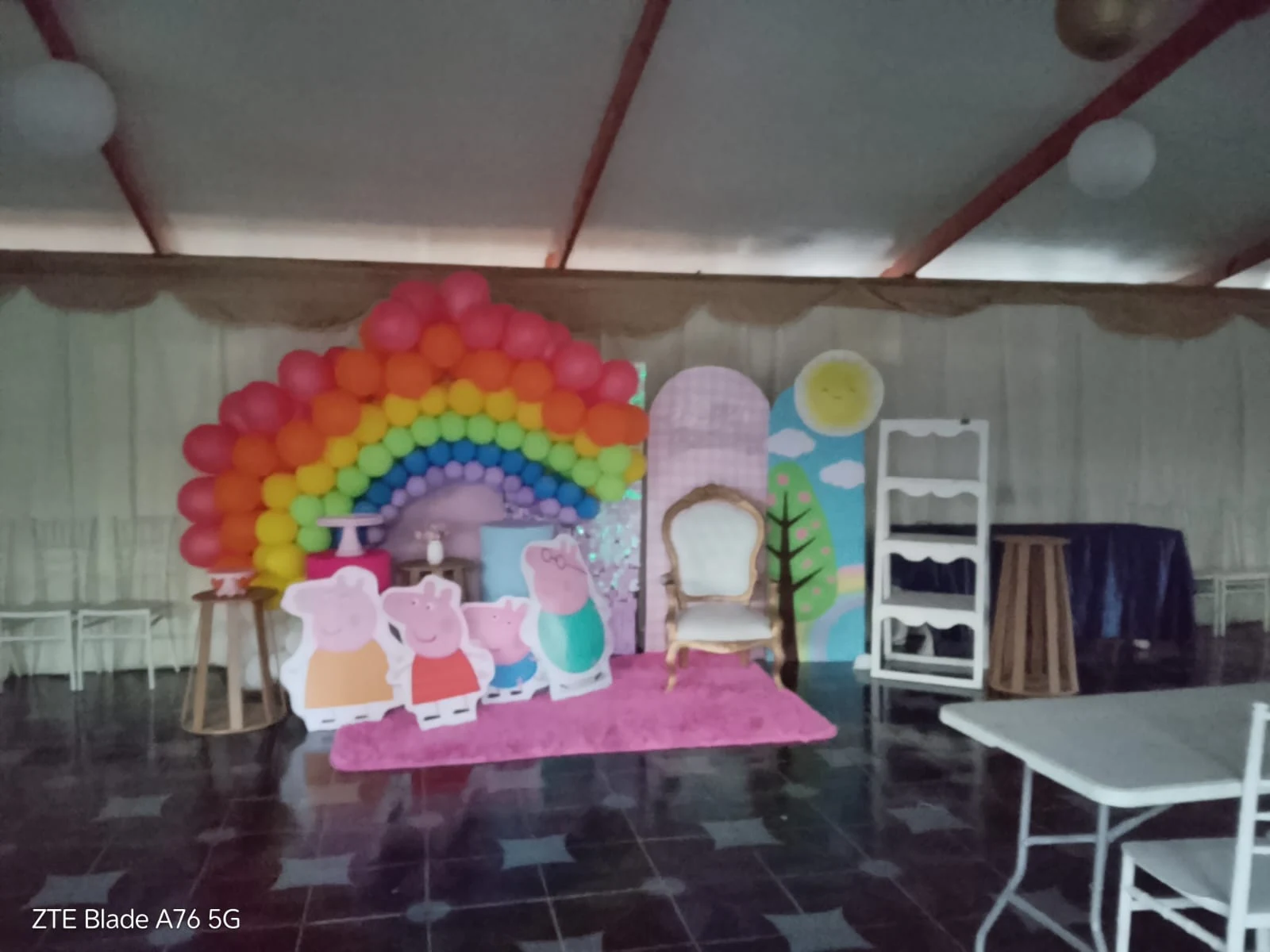 Vista del salón con un montaje de cumpleaños infantil, arcoíris de globos y figuras de Peppa Pig.
