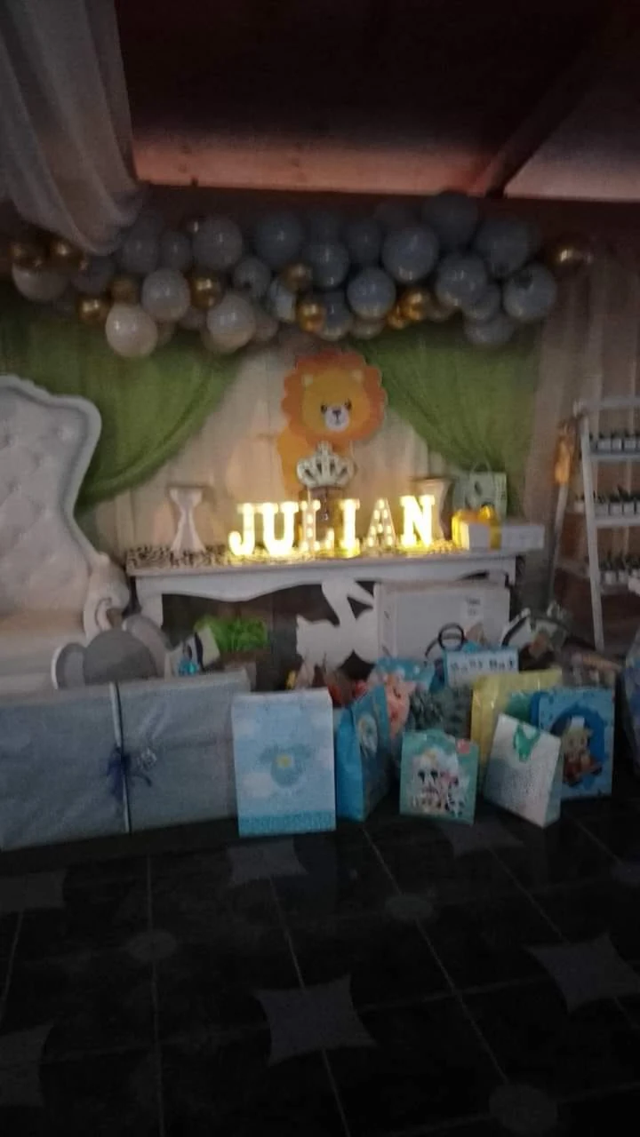 Montaje de cumpleaños con temática de safari, globos, figura de león, letras luminosas y regalos.