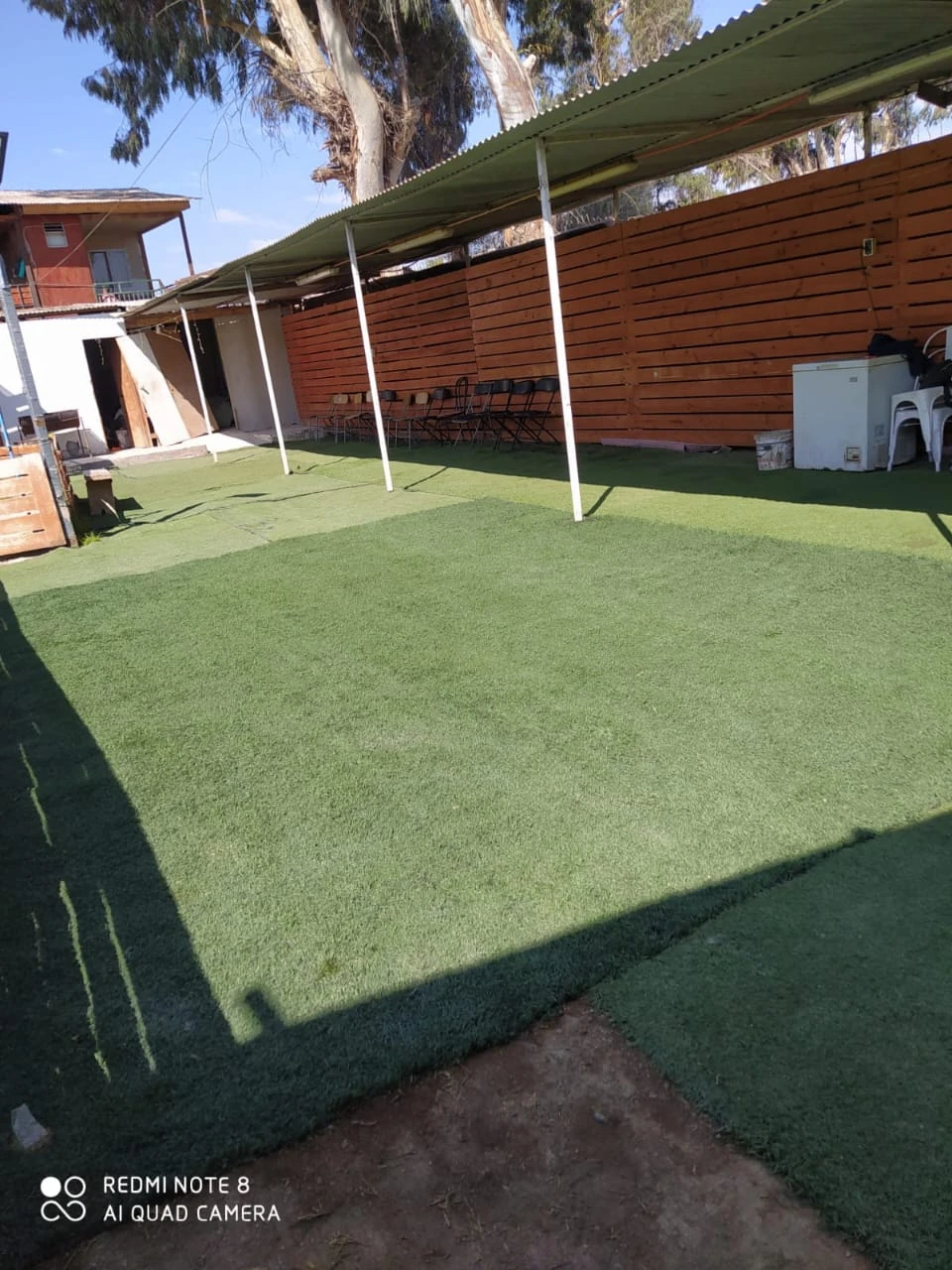 Área exterior de Manantial con césped y un sector techado con sillas para reunirse durante el paseo de curso.